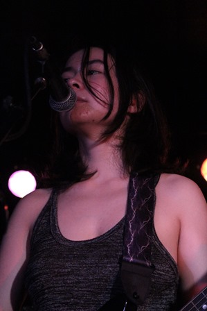 A photograph of Mitski at her concert in Toronto singing into a microphone.